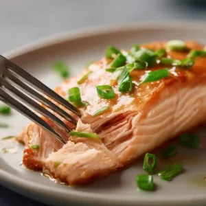Flaky steamed salmon with scallions on plate