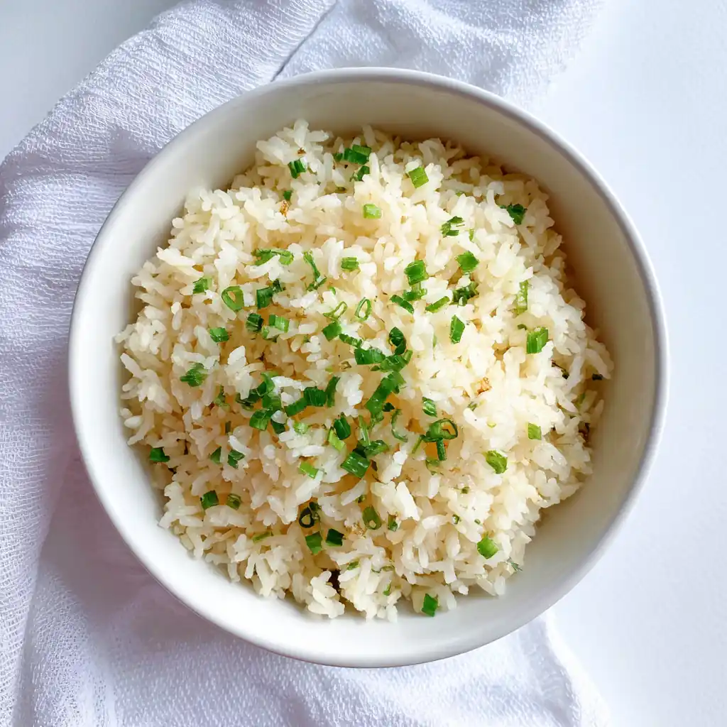 Rice steamer garlic butter rice served neatly in a white ceramic bowl