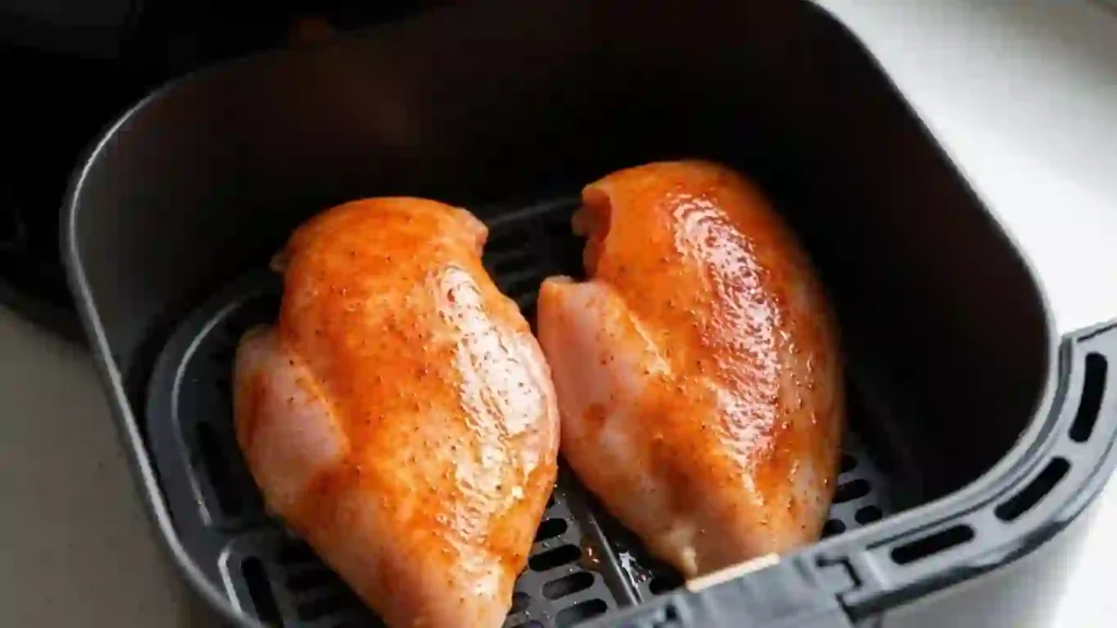Chicken breasts arranged in an air fryer basket ready to cook