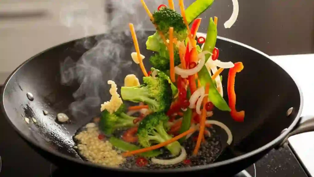 Garlic and ginger cooking in a wok with broccoli, carrots, and bell pepper for a stir-fry